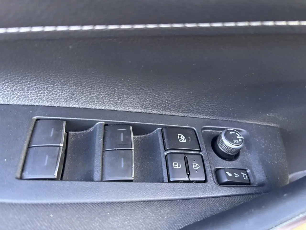 Panneau de commandes des vitres et rétroviseurs côté gauche intérieur d'une Toyota Corolla hybride bleu clair 2020.