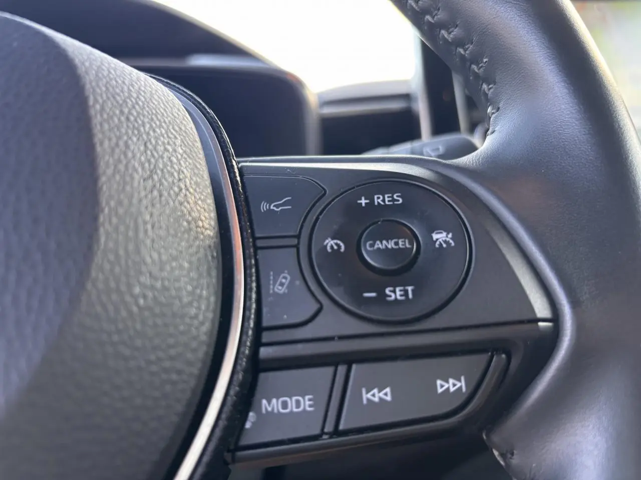 Gros plan sur les commandes au volant droit de la Toyota Corolla Hybride 2020, finition Dynamic Business, avec boutons de régulateur et multimédia.