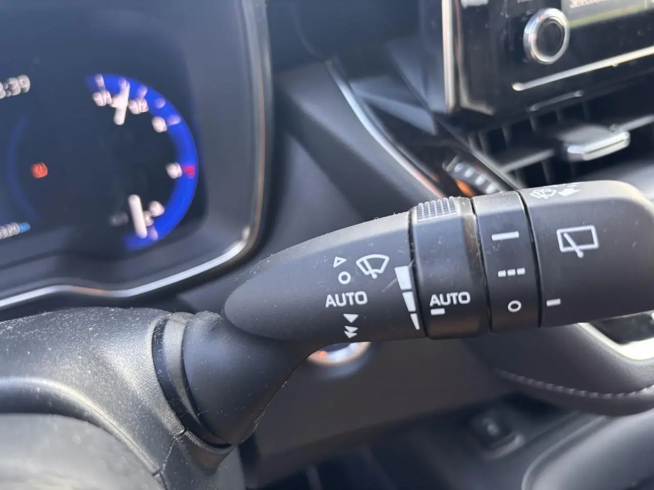 Gros plan sur la commande d'essuie-glace à gauche du volant dans l'habitacle d'une Toyota Corolla hybride 2020.