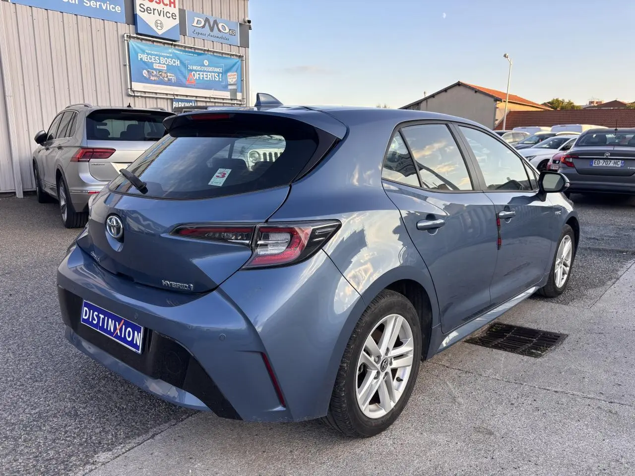 Vue 3/4 arrière droite d'une Toyota Corolla hybride bleu clair 2020 avec feux arrière LED et jantes alliage.