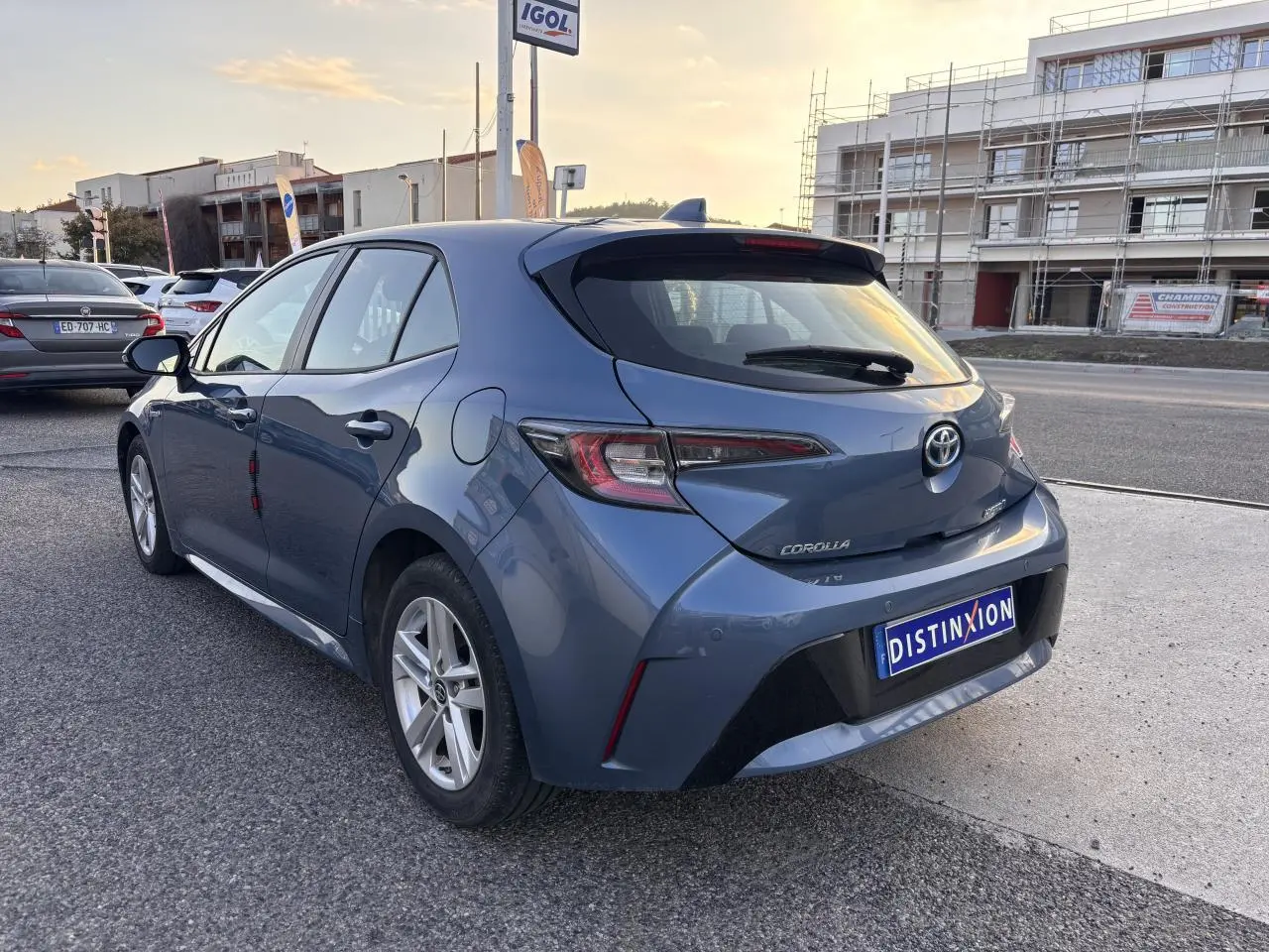 Vue 3/4 arrière droite d'une Toyota Corolla hybride bleu clair 2020 avec finition Dynamic Business sur parking extérieur.