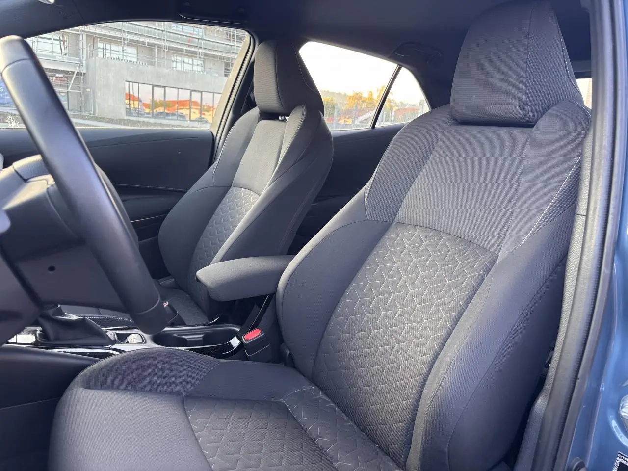 Vue intérieure des sièges avant en tissu gris avec motifs géométriques dans une Toyota Corolla bleu clair 2020 hybride.