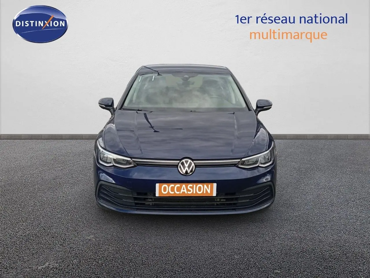 Vue frontale d'une Volkswagen Golf VIII bleu Atlantique métallisé avec plaque "OCCASION" sur un sol gris.