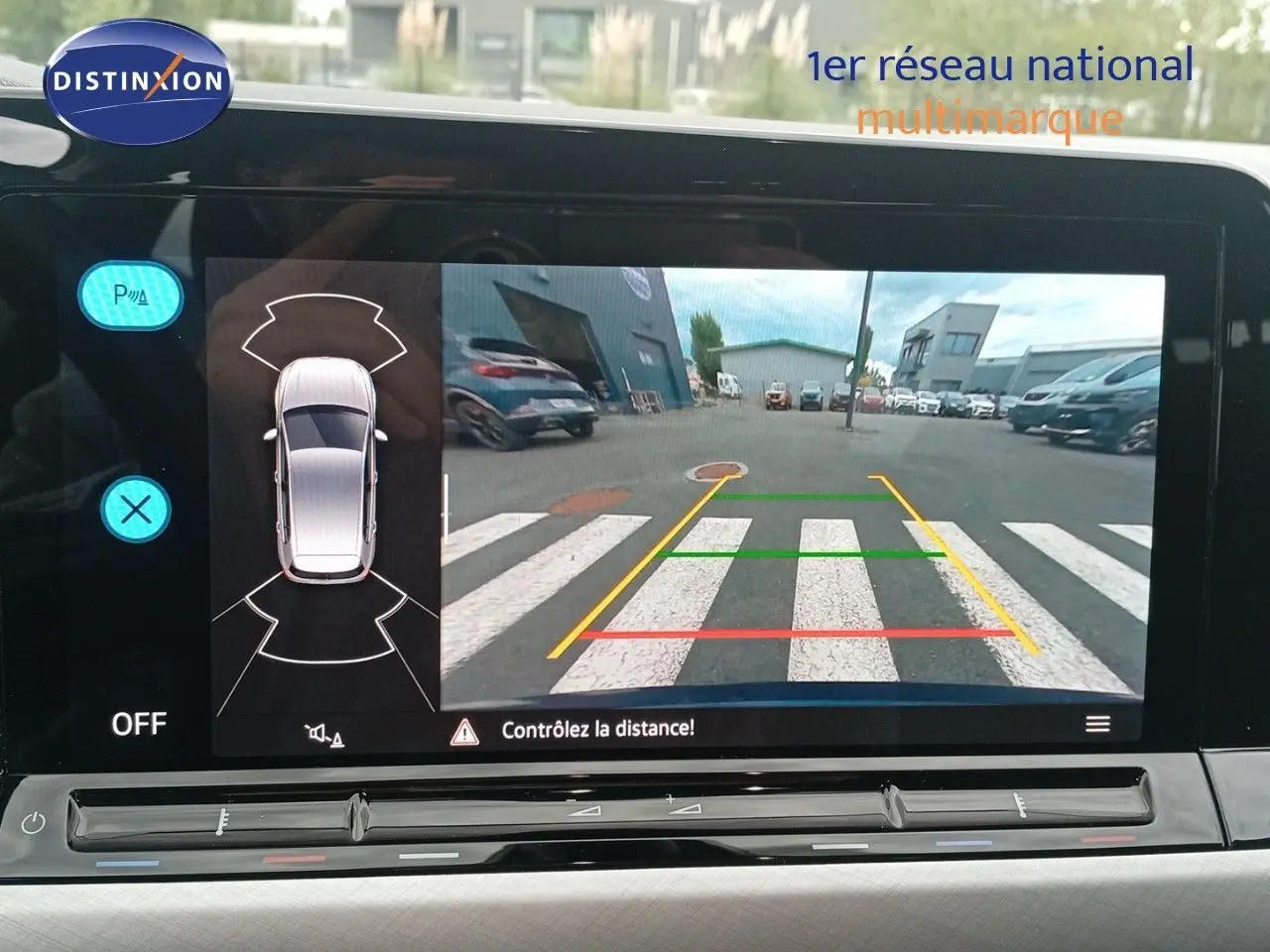 Écran intérieur affichant la caméra de recul avec vue arrière et lignes de guidage d'une Volkswagen Golf VIII bleu Atlantique.