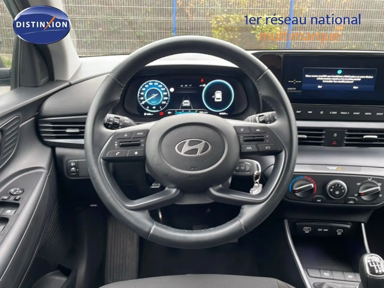 Vue intérieure du tableau de bord et volant cuir de la Hyundai i20 2025 avec écran digital et commandes au volant.