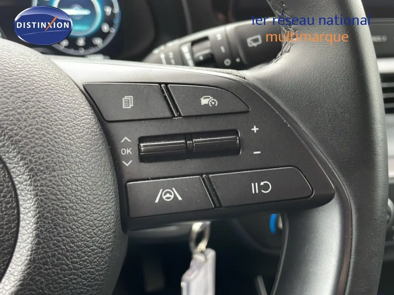 Gros plan sur les commandes au volant noir de la Hyundai i20 2025, version 1.0 TGDI en tissu et cuir.