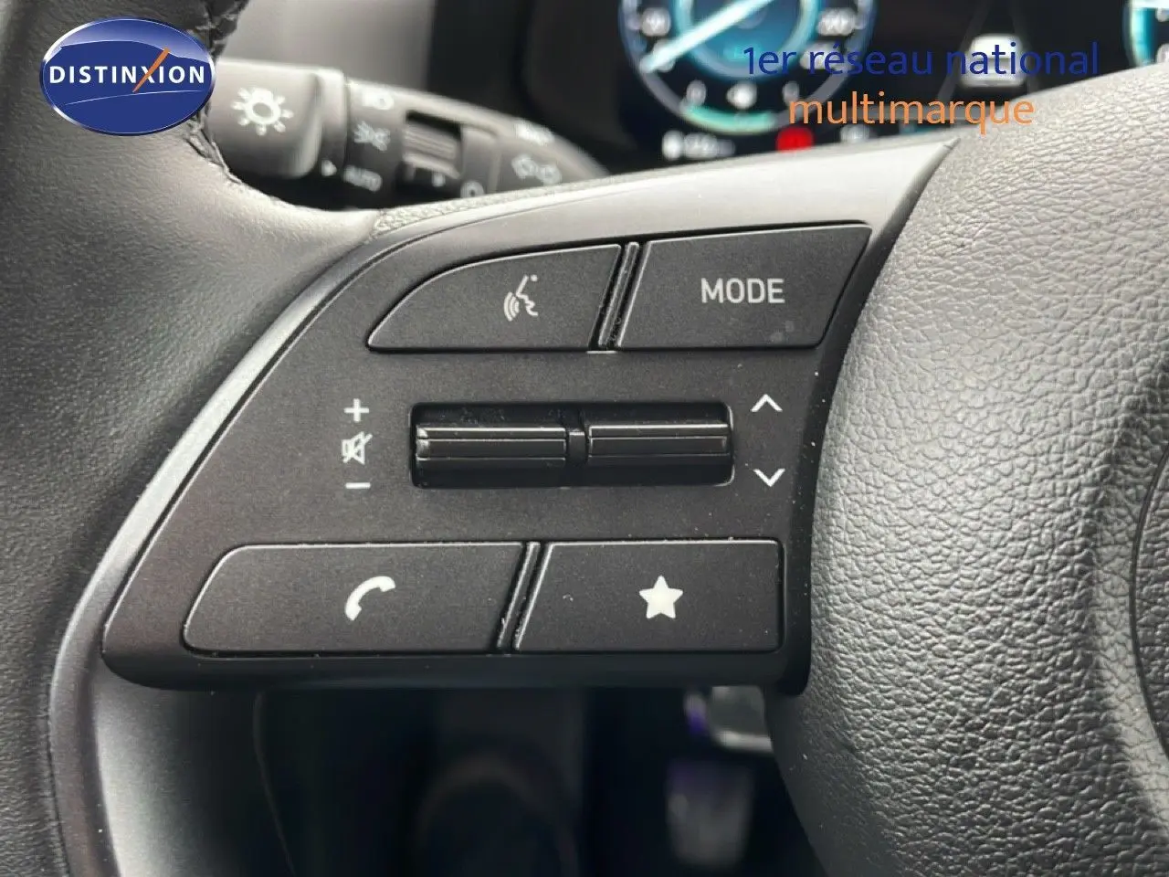 Gros plan sur les commandes au volant côté gauche d'une Hyundai i20 2025 vert mangrove métal, avec boutons multifonctions.