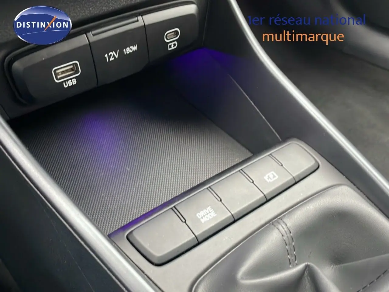 Gros plan sur la console centrale avec prises USB, bouton Drive Mode et finition noire intérieure de la Hyundai i20 2025.