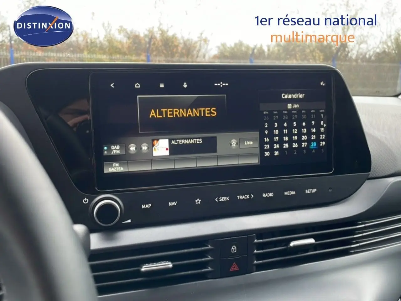 Écran tactile central du tableau de bord de la Hyundai i20 2025, affichant radio et calendrier, intérieur noir moderne.