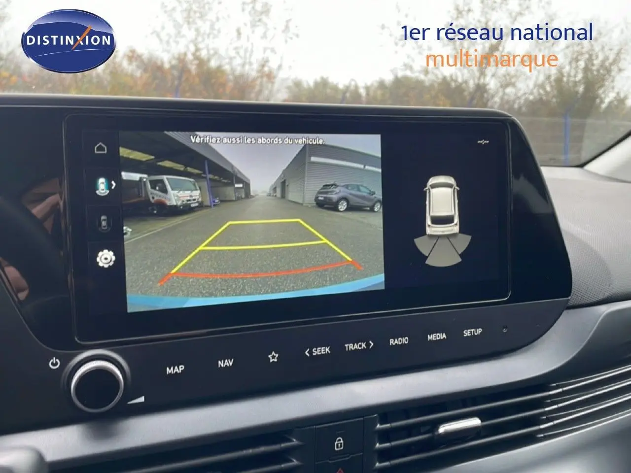 Écran central montrant la caméra de recul d'une Hyundai i20 2025, avec vue arrière et aides au stationnement.