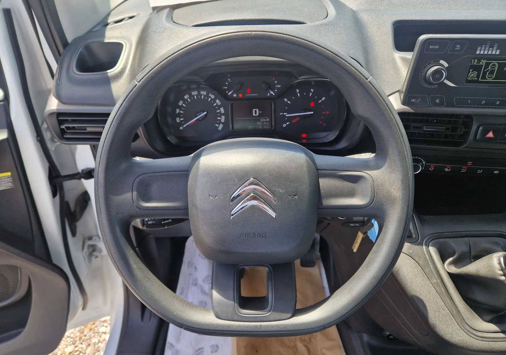 Vue intérieure centrée sur le volant noir du Citroën Berlingo blanc, tableau de bord et commandes visibles en arrière-plan.