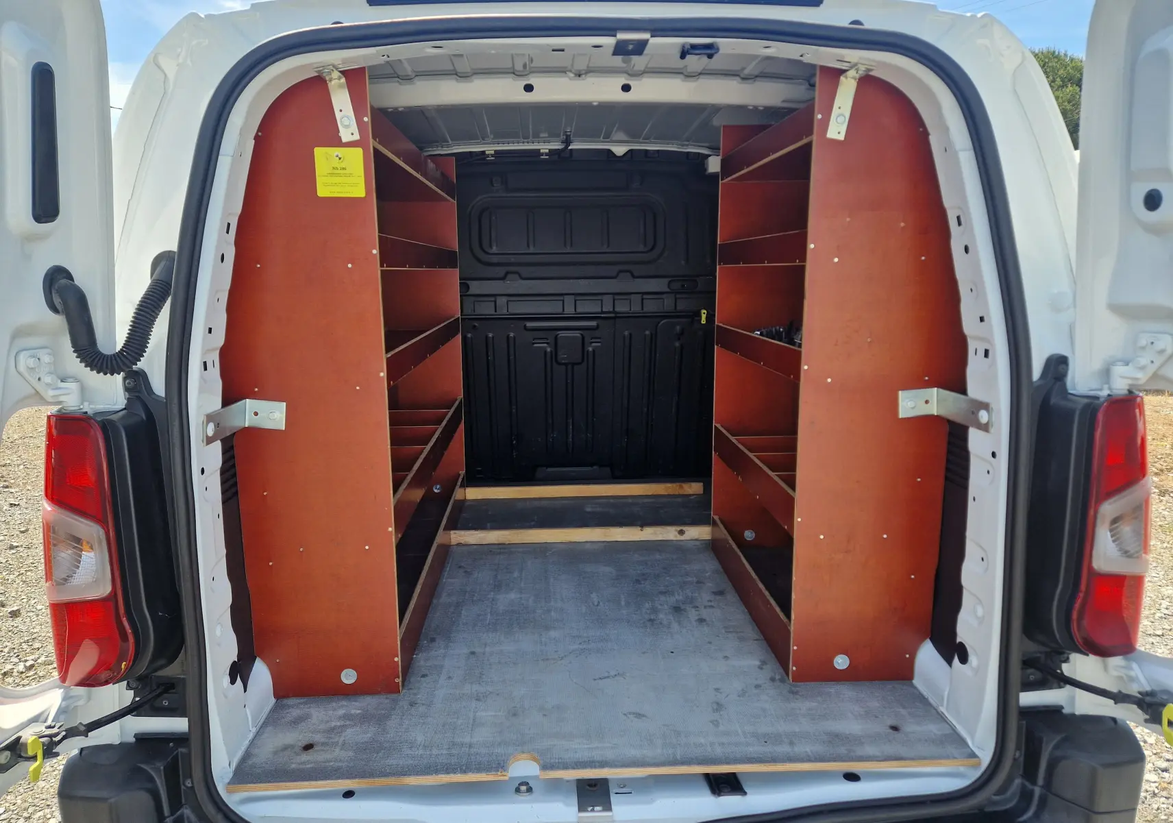 Vue arrière ouverte du Citroën Berlingo blanc 2020, montrant les étagères en bois intégrées dans l’espace de chargement.