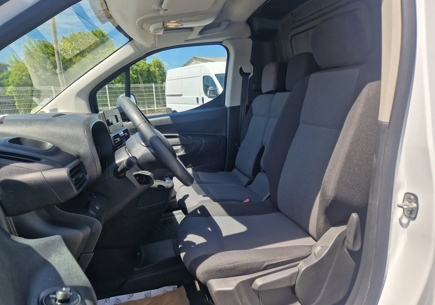 Vue intérieure côté conducteur du Citroën Berlingo blanc 2020, montrant les sièges avant et le tableau de bord.