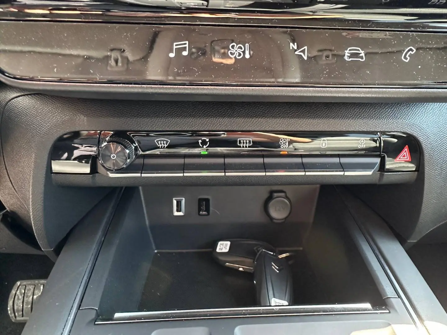 Vue rapprochée de la console centrale du Citroën C5 Aircross 2025 avec commandes climatisation et clé dans le rangement.