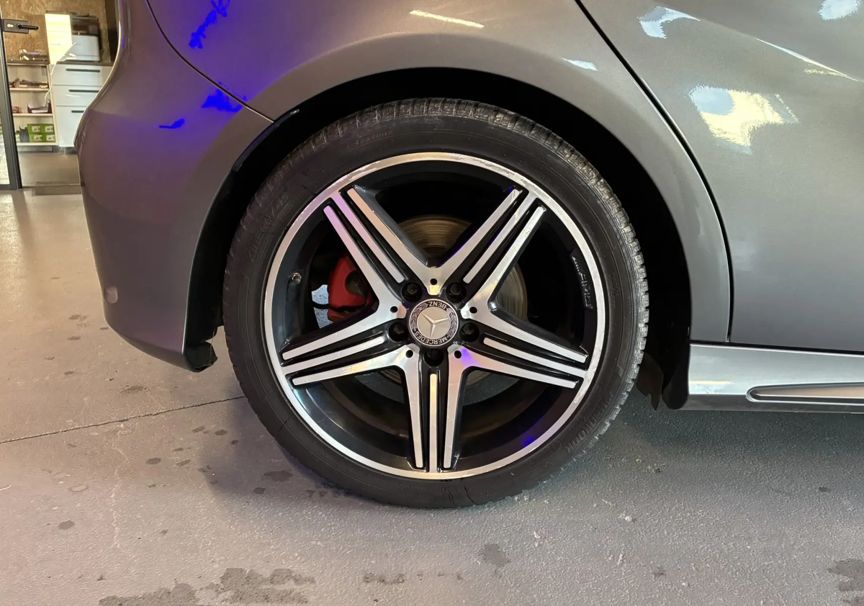 Gros plan sur la roue arrière droite gris métallisé d'une Mercedes Classe A 250 AMG Sport avec jante alliage 5 branches et étrier de frein rouge.