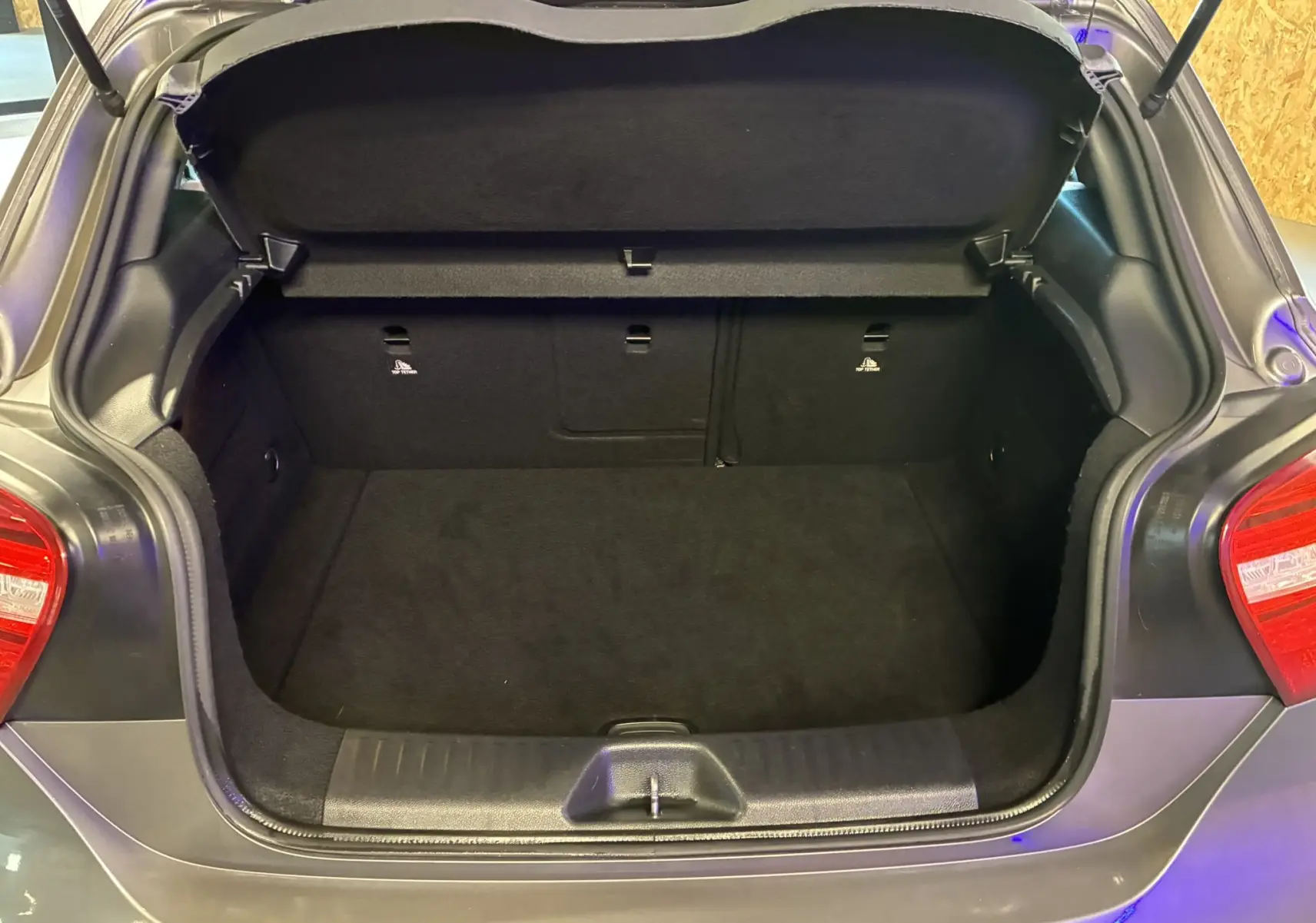 Coffre ouvert vu de l'arrière d'une Mercedes Classe A 250 AMG Sport gris, montrant l'espace de chargement vide.