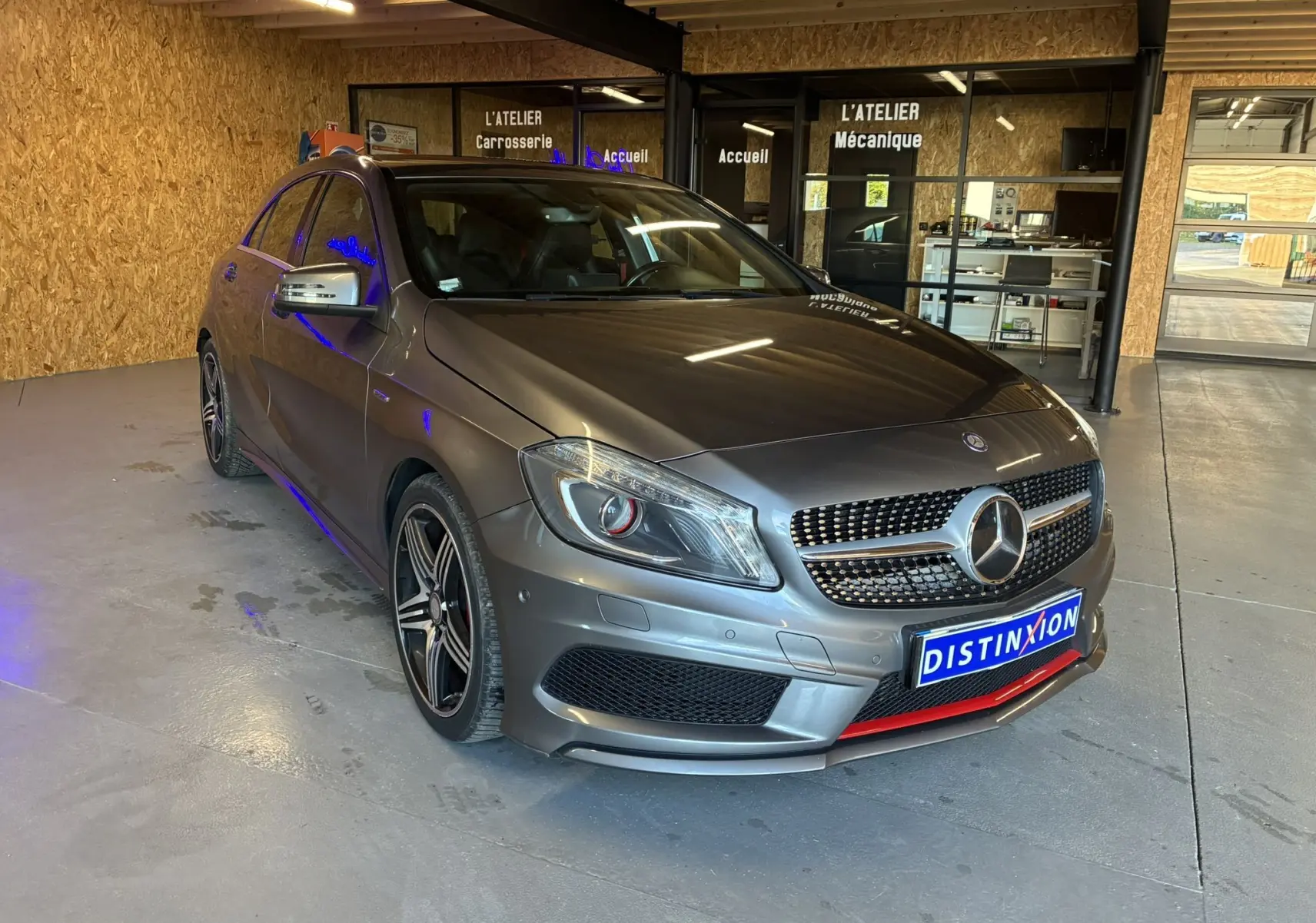 Mercedes Classe A 250 AMG Sport gris vue 3/4 avant droit, avec calandre AMG et jantes alliage bicolores dans un atelier.