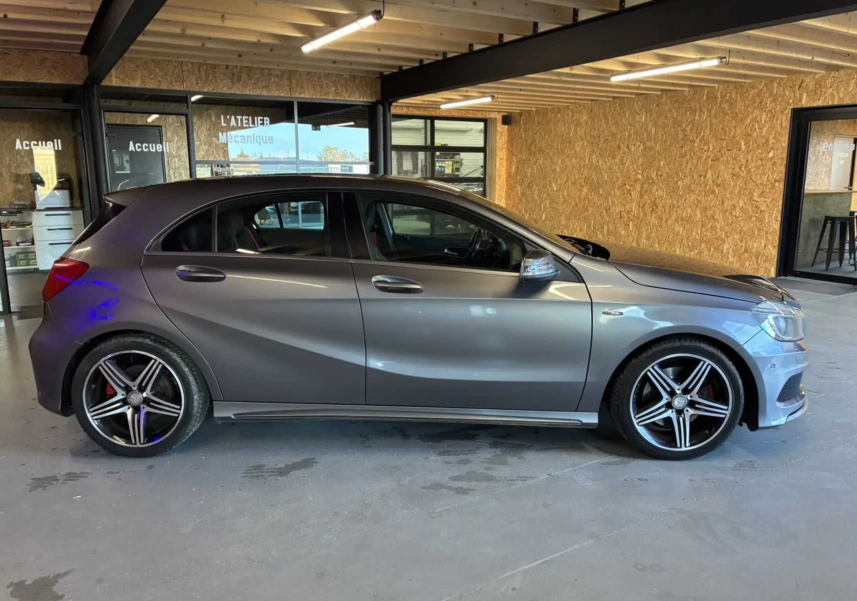 Profil droit d'une Mercedes Classe A 250 AMG Sport gris métallisé avec jantes alliage 5 branches bicolores.