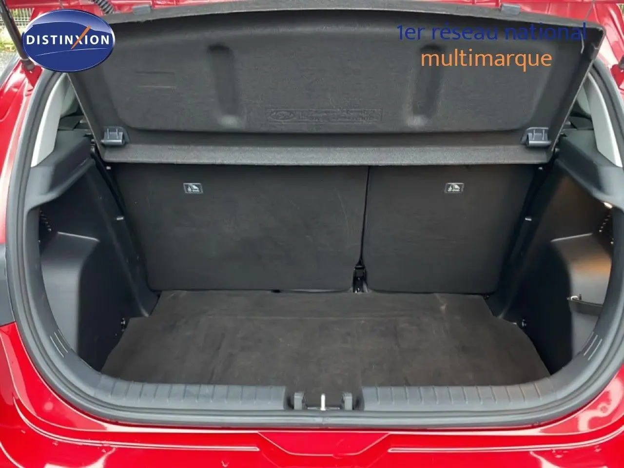 Coffre ouvert vu de l'arrière d'une Hyundai i20 rouge Dragon Metal, montrant l'espace de chargement vide.