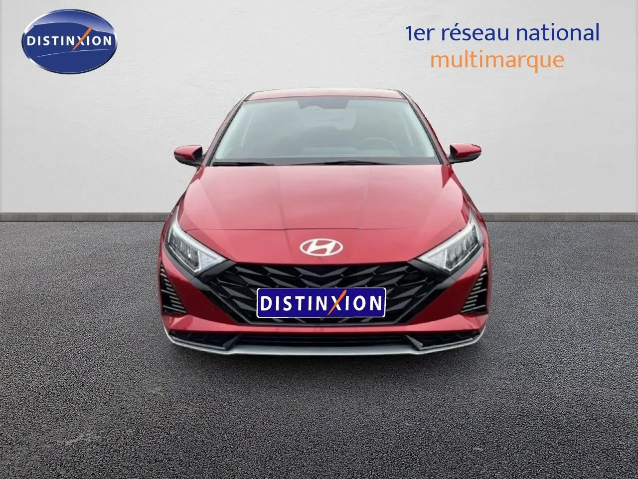 Vue frontale d'une Hyundai i20 2025 rouge dragon métal avec calandre noire et phares LED distinctifs.
