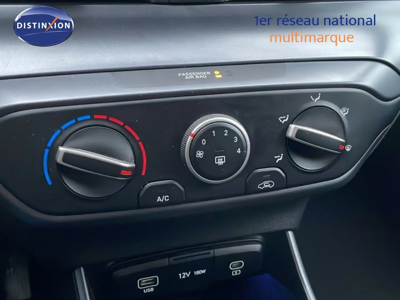 Gros plan sur les commandes de climatisation manuelle et les ports USB d'une Hyundai i20 rouge Dragon Metal 2025.