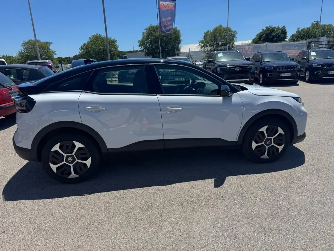 Citroën C4 hybride blanc vue de profil côté gauche, avec toit noir et jantes alliage 18 pouces.