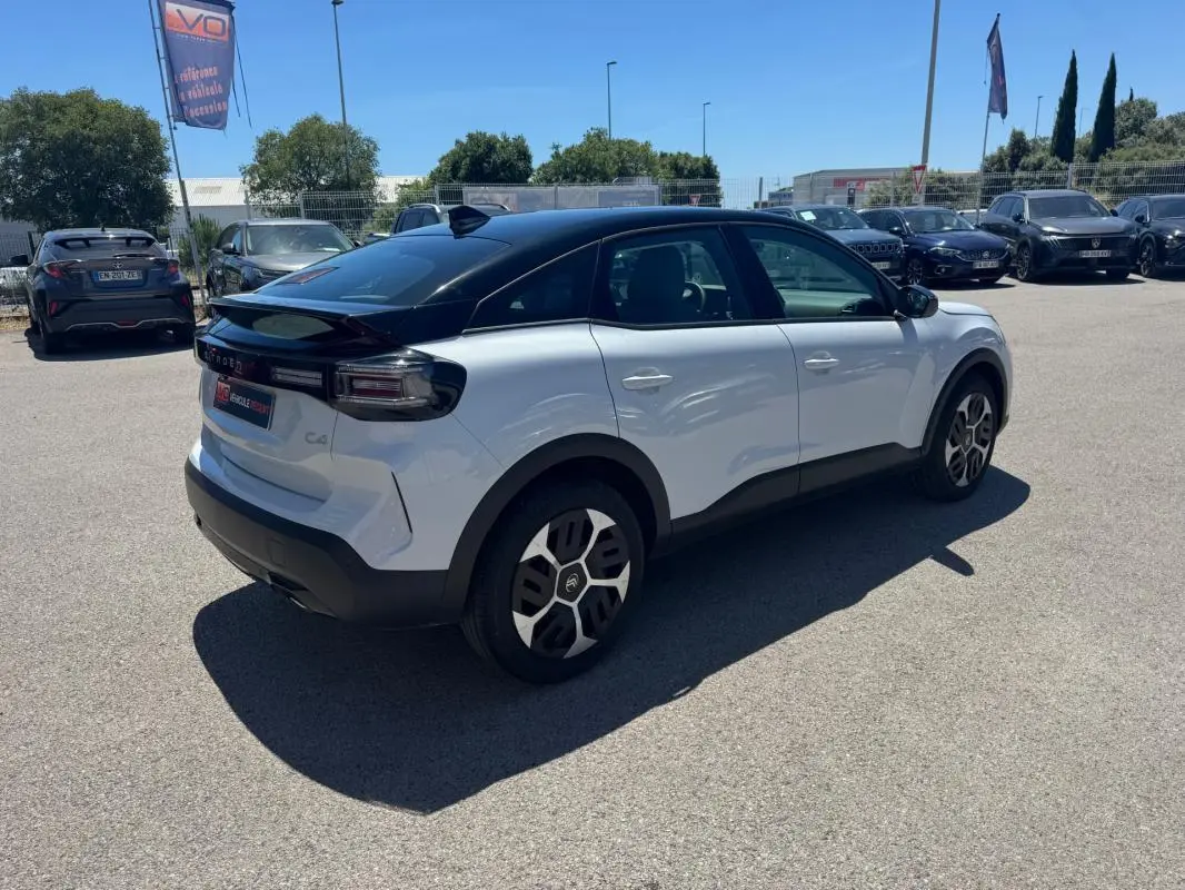 Citroën C4 hybride blanc vue 3/4 arrière droit avec toit noir et jantes alliage 18 pouces.