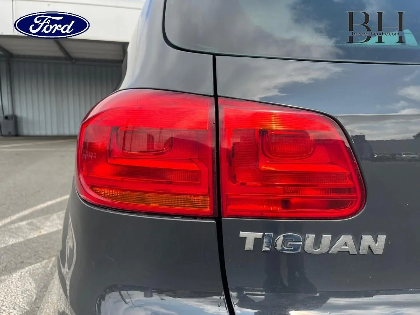 Gros plan sur le feu arrière gauche d’un Volkswagen Tiguan gris poivre avec le logo Tiguan visible sur le hayon.
