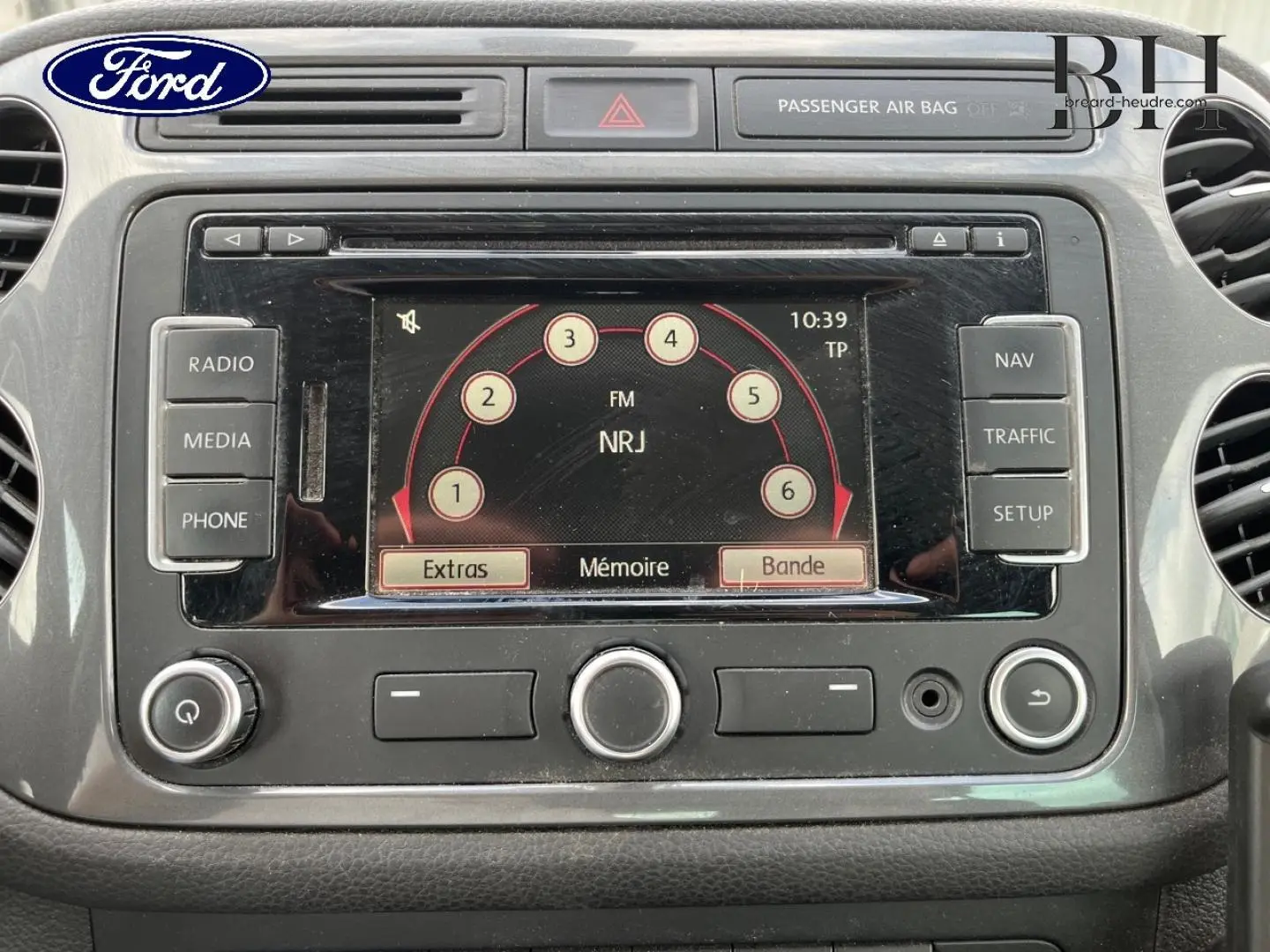 Vue rapprochée de la console centrale grise d’un Volkswagen Tiguan 2014 avec écran tactile et commandes radio visibles.