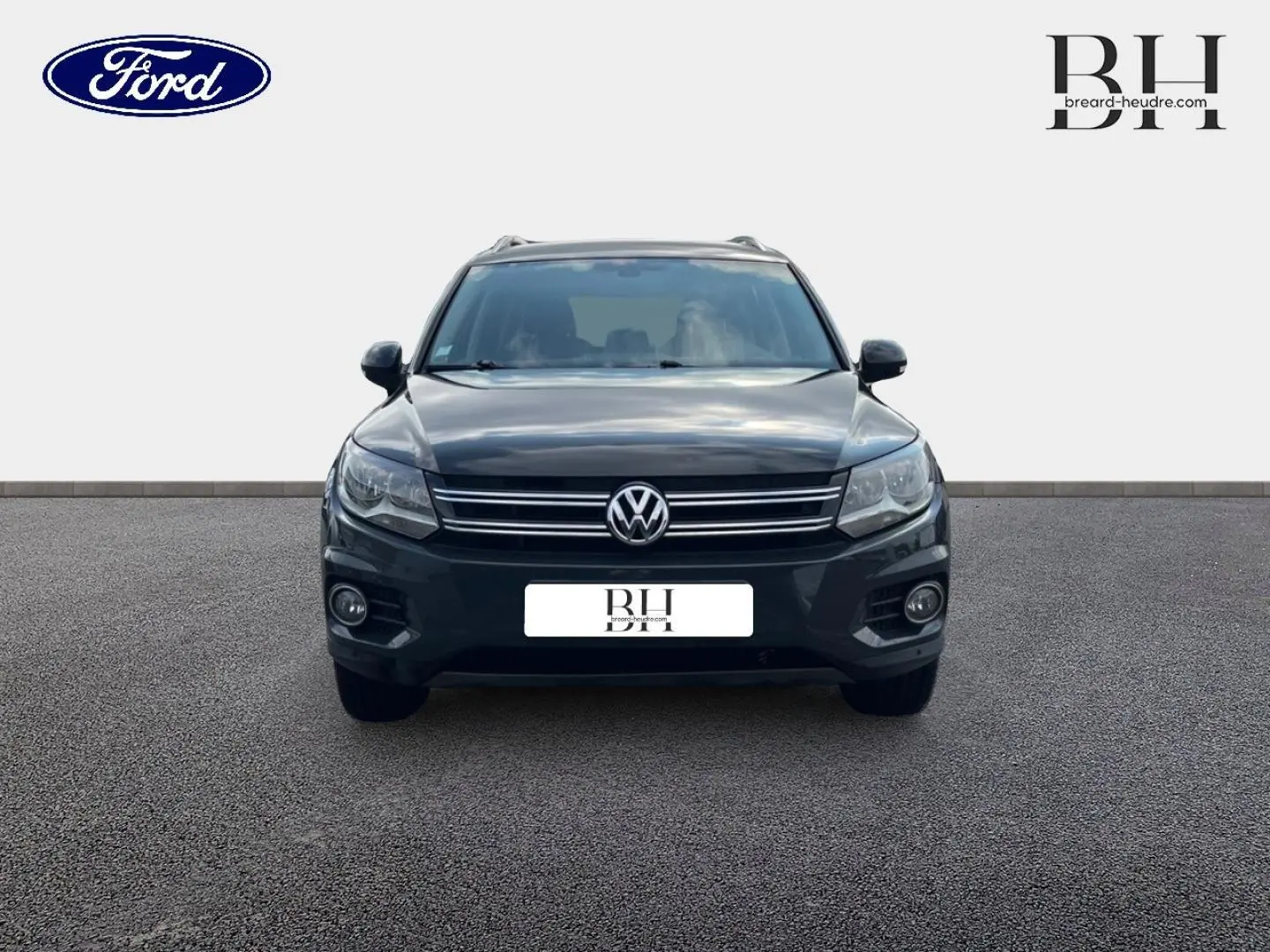 Vue avant d'un Volkswagen Tiguan gris poivre avec calandre chromée et phares halogènes visibles.