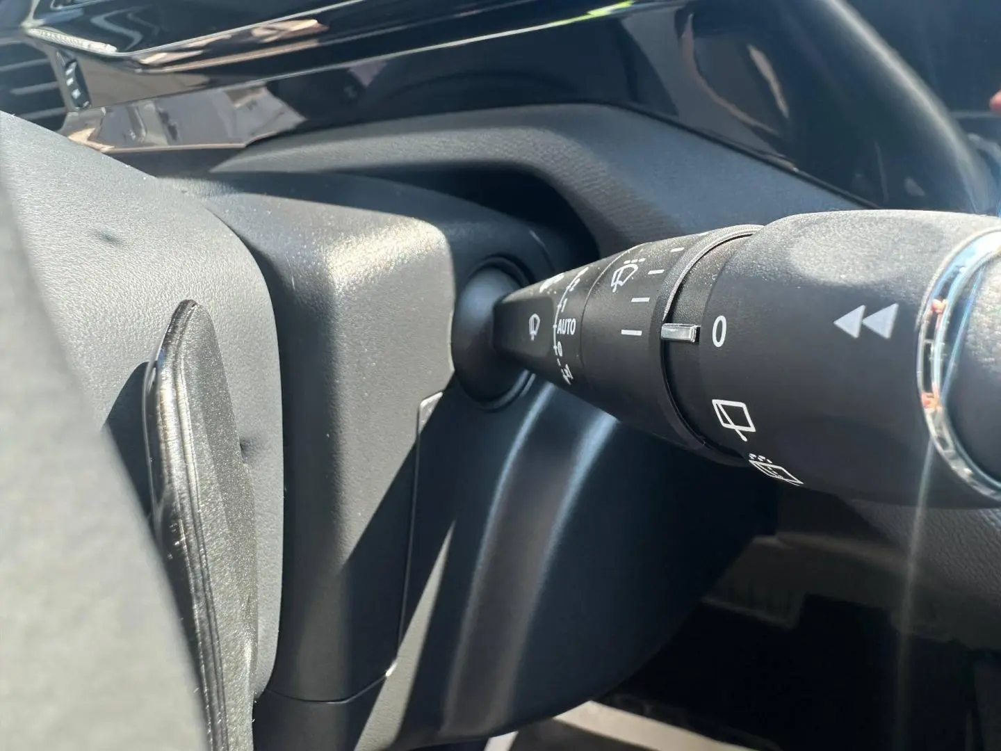Gros plan sur la commande des essuie-glaces côté droit du volant dans l’habitacle noir du Peugeot 308 SW blanc.