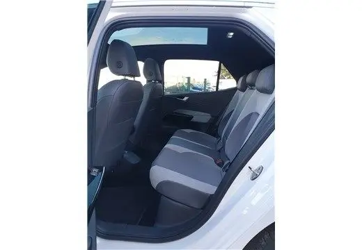 Vue latérale côté droit sur l'intérieur arrière du Volkswagen ID.3 blanc glacier, montrant les sièges en tissu bicolore.