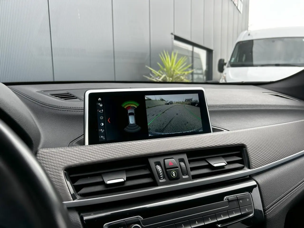 Vue rapprochée du tableau de bord du BMW X2 bleu Misano, avec écran affichant la caméra de recul et les commandes centrales.