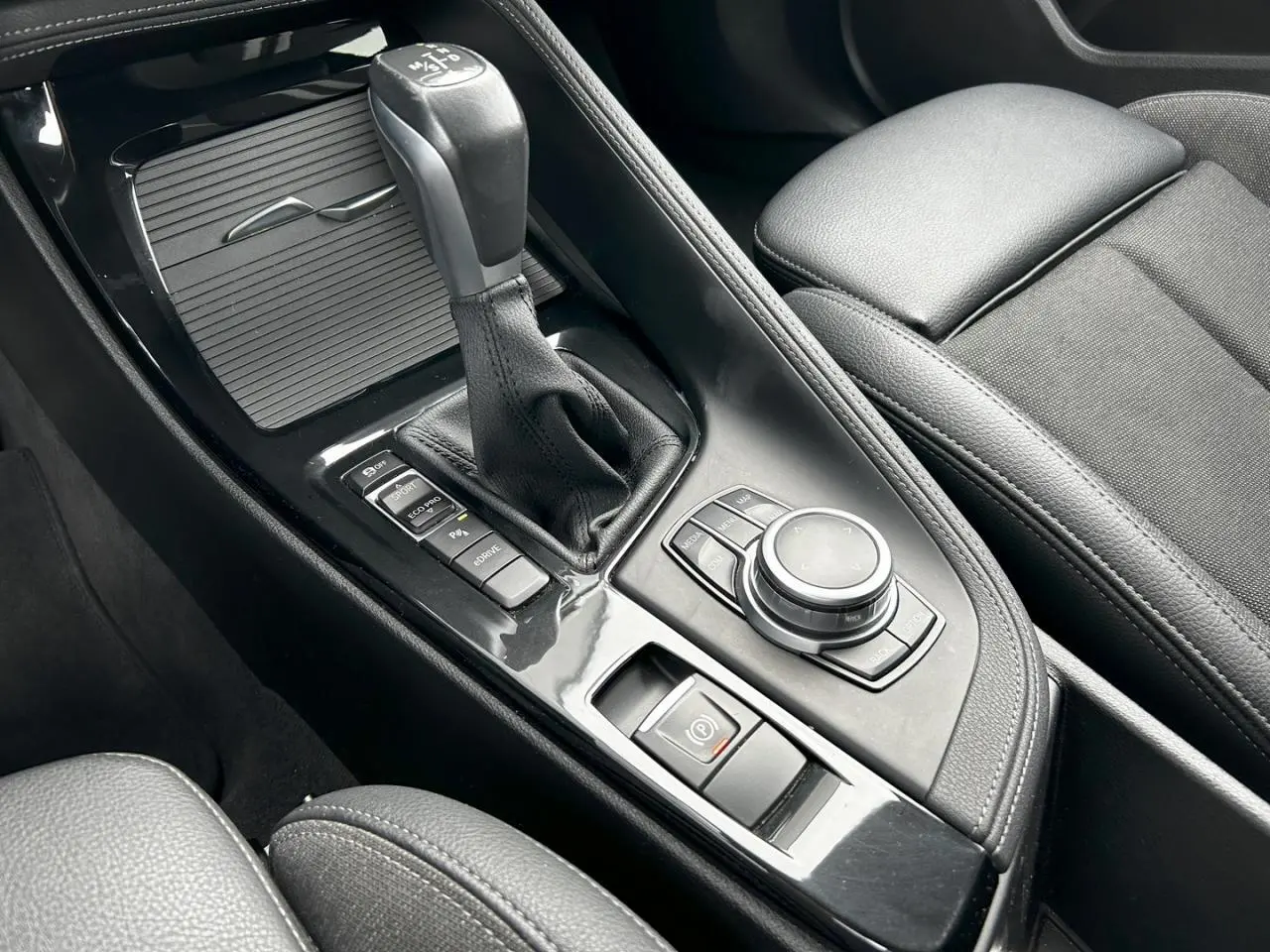 Gros plan sur la console centrale noire avec levier de vitesses automatique et commandes multifonctions du BMW X2 F39.