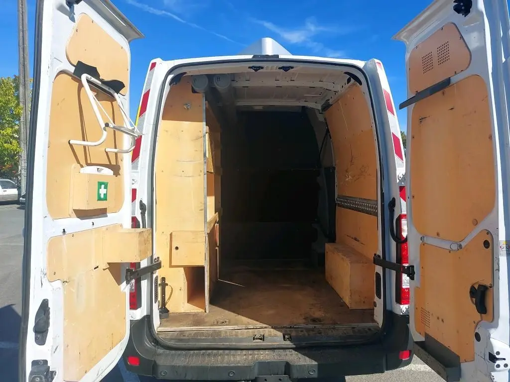 Vue arrière du Renault Master blanc avec portes ouvertes, montrant l'intérieur utilitaire en bois clair.