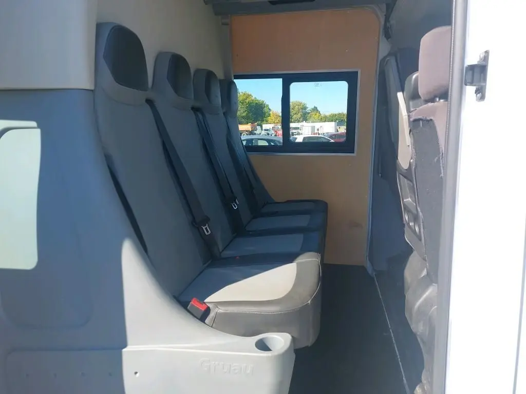 Vue intérieure latérale droite des sièges gris du Renault Master Cabine Approfondie blanc, version 7 places avec fenêtre arrière.