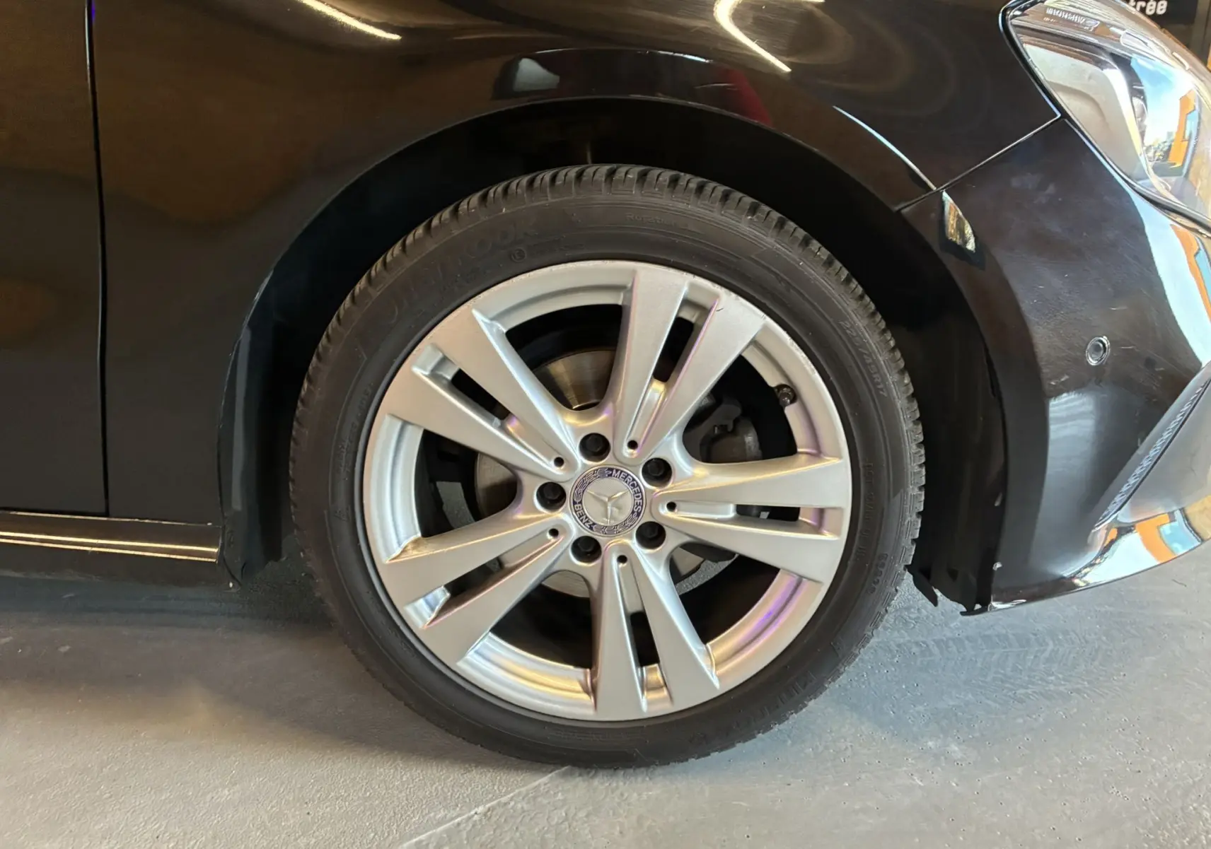 Gros plan sur la roue avant droite d'une Mercedes Classe A 180 CDI noire, mettant en valeur la jante alliage argentée.