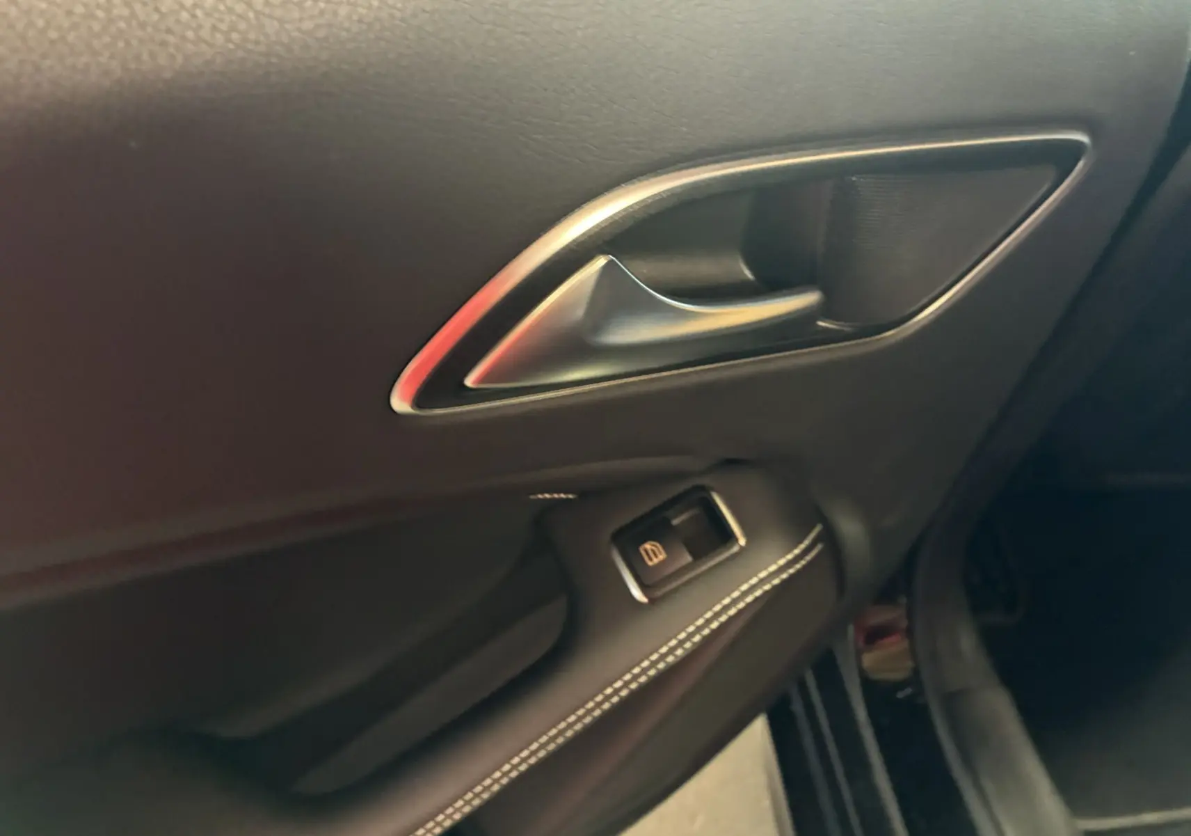 Poignée de porte intérieure côté gauche en cuir noir avec surpiqûres blanches sur une Mercedes Classe A 180 CDI Sensation 2018.