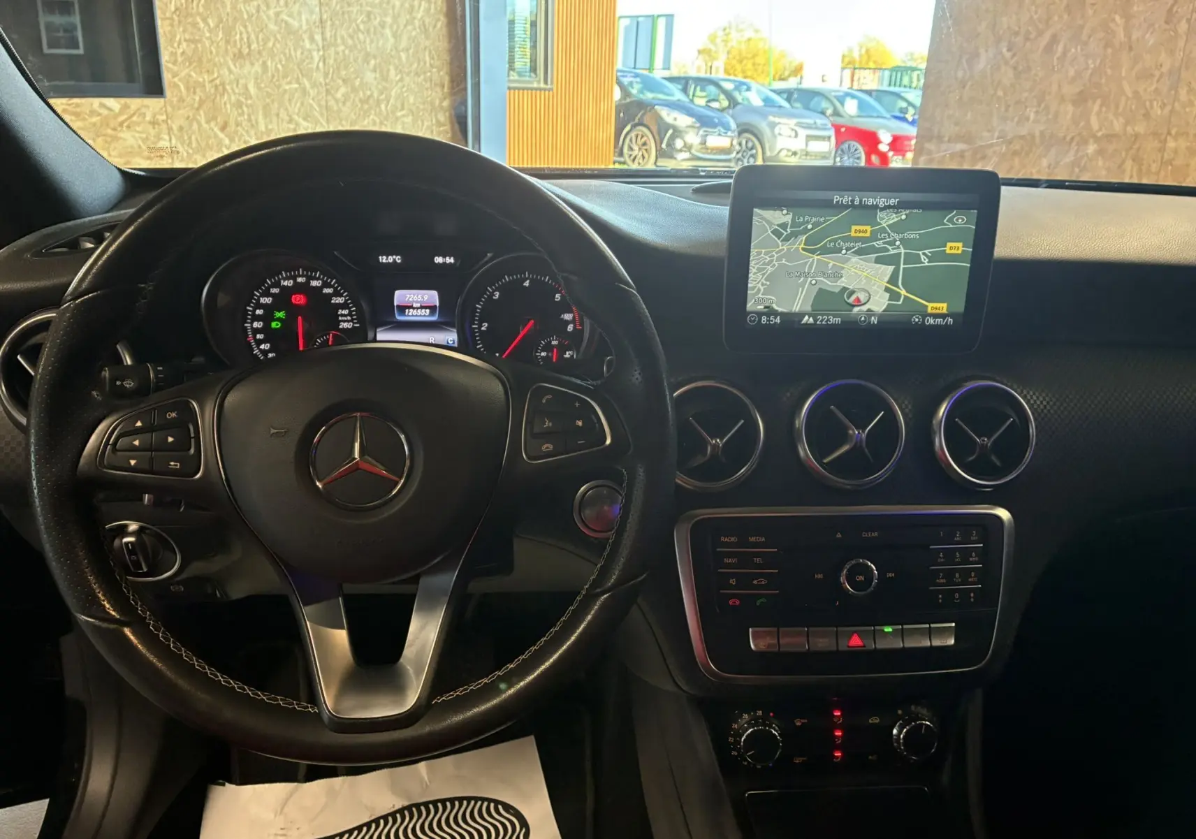 Vue intérieure du tableau de bord et volant noir d'une Mercedes Classe A 180 CDI Sensation avec écran GPS et aérateurs ronds chromés.