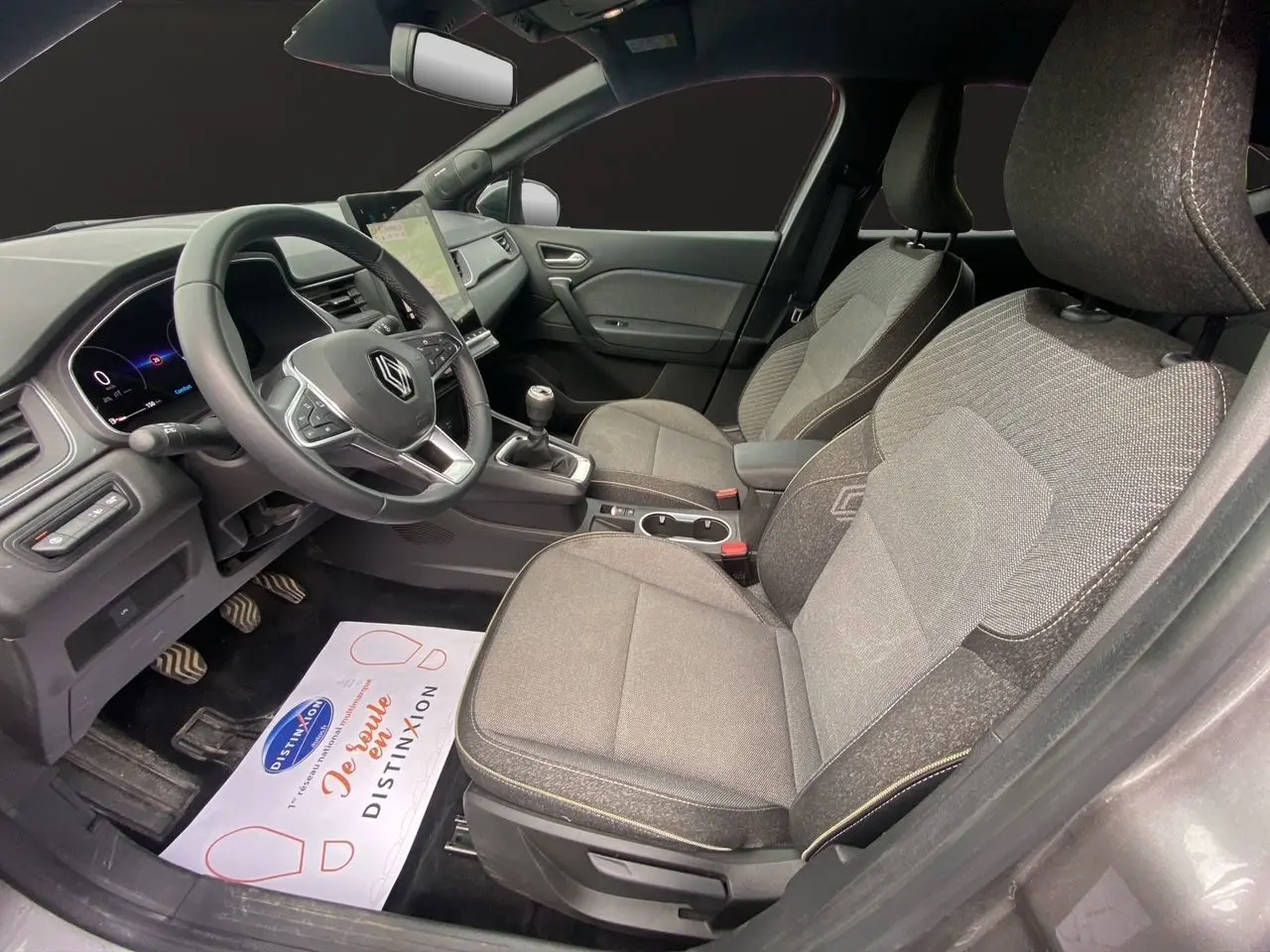 Vue intérieure côté conducteur du Renault Captur 2025 avec sièges tissu gris et tableau de bord moderne.