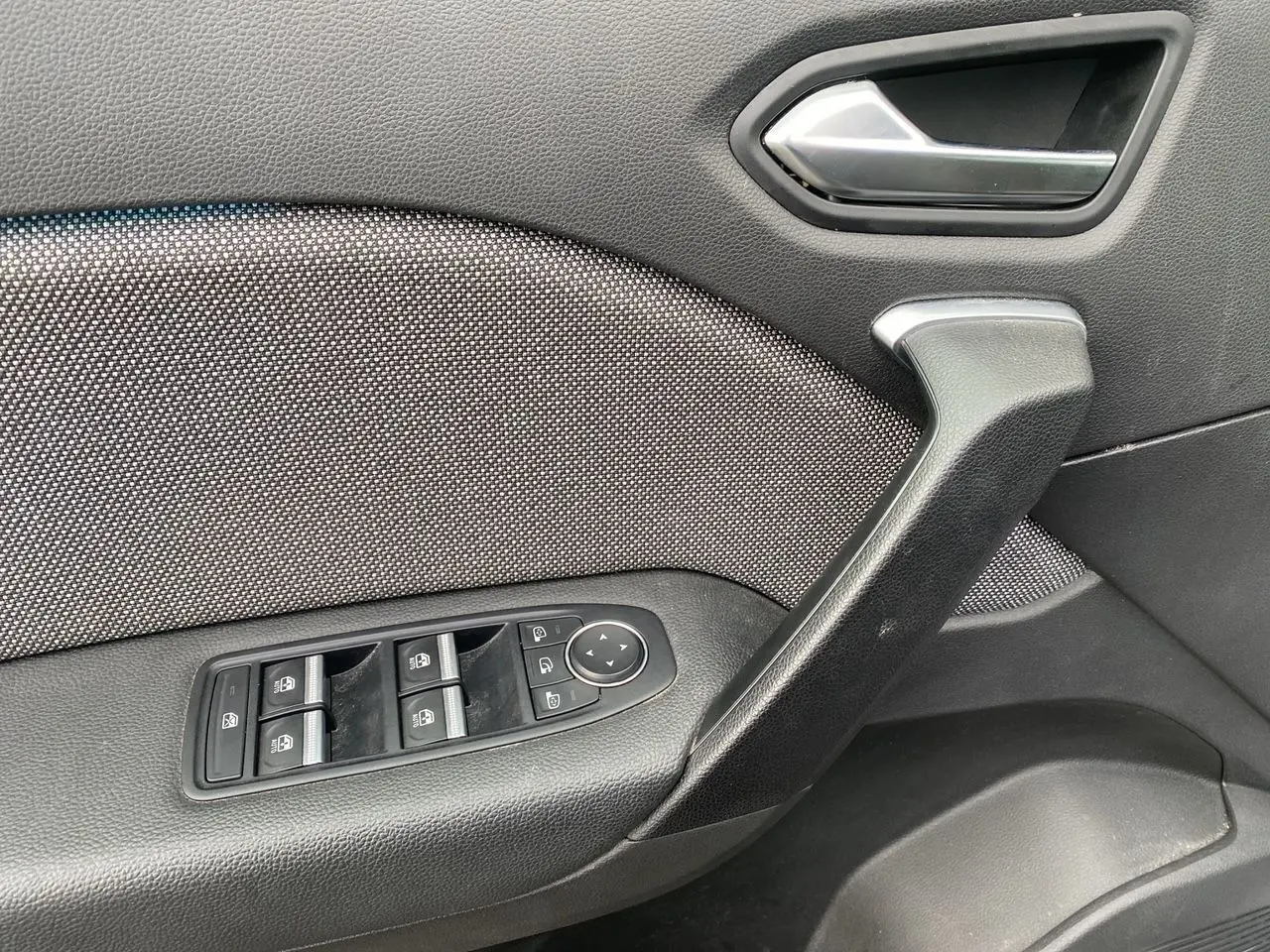 Détail de la porte côté conducteur du Renault Captur gris Cassiopée, avec commandes des vitres et rétroviseurs électriques.