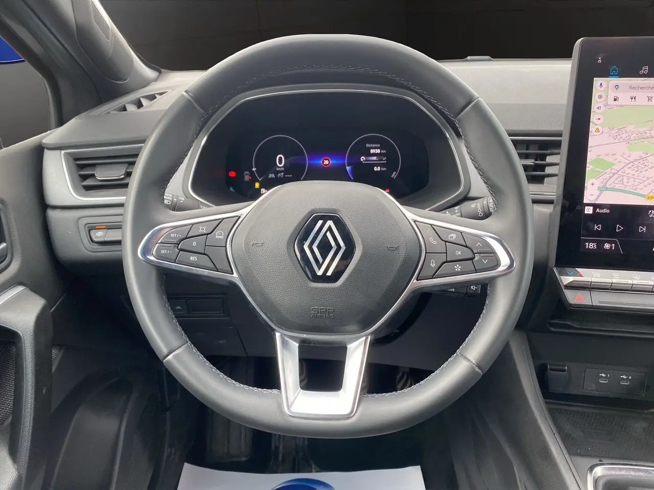 Vue intérieure centrée sur le volant noir de la Renault Captur 2025 avec tableau de bord digital et écran tactile GPS.