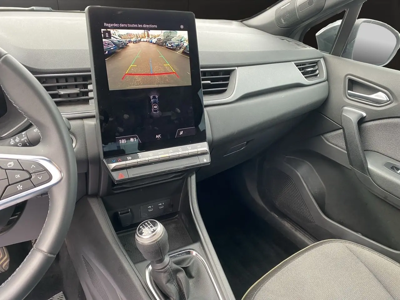 Vue intérieure côté passager du tableau de bord noir et écran tactile affichant la caméra de recul du Renault Captur 2025.