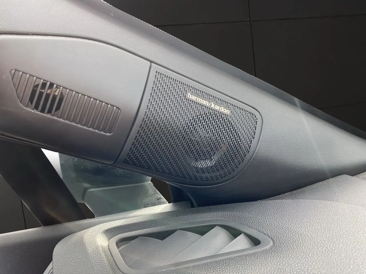 Gros plan sur l'enceinte Harman/Kardon intégrée côté gauche du tableau de bord du Renault Captur gris Cassiopée.