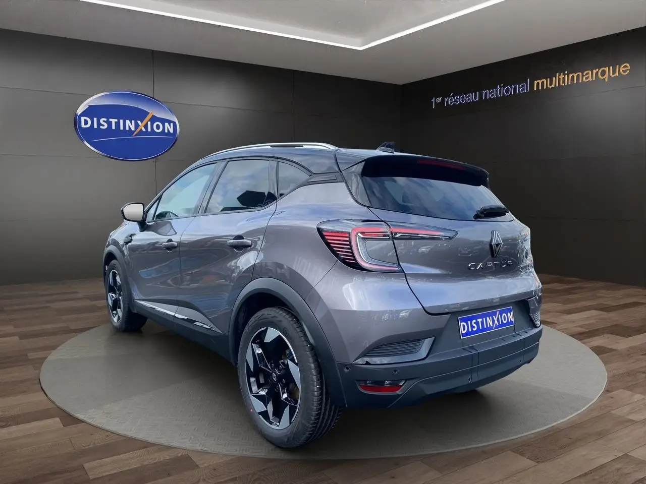 Vue 3/4 arrière droite du Renault Captur gris Cassiopée avec toit noir et jantes alu 18 pouces, barres de toit visibles.