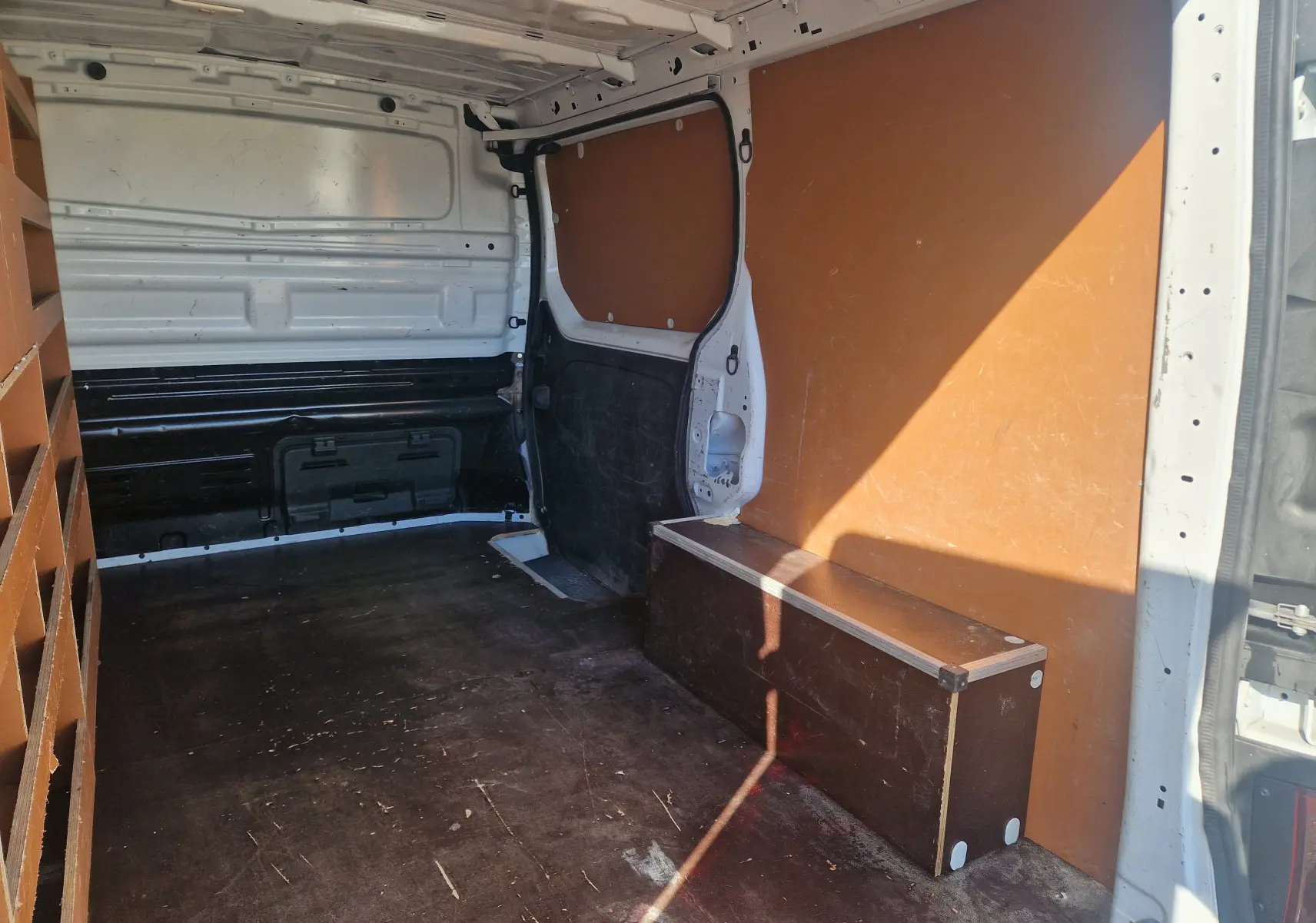 Vue intérieure arrière droite du Renault Trafic Fourgon blanc 2021, montrant l'aménagement bois et l'espace de chargement.