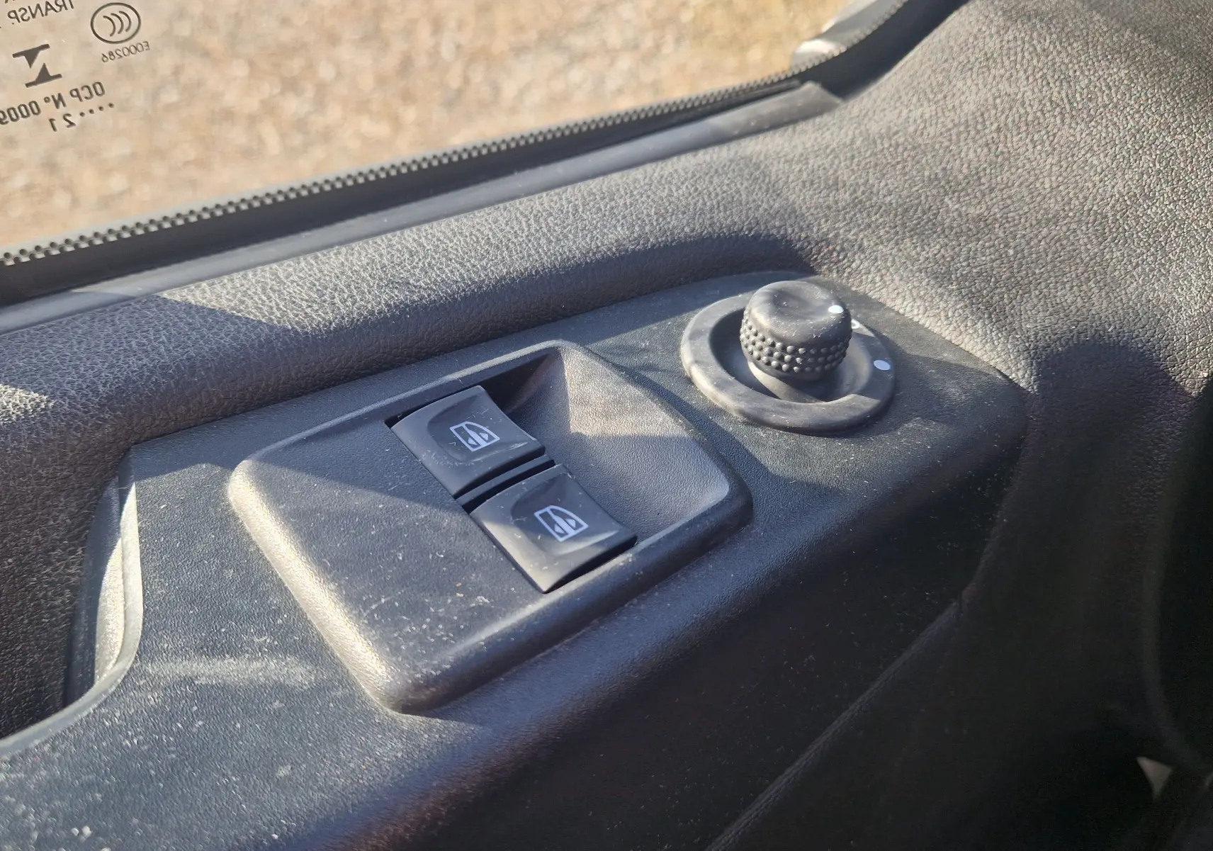 Gros plan sur les commandes de lève-vitres et réglage des rétroviseurs côté conducteur du Renault Trafic Fourgon blanc 2021.