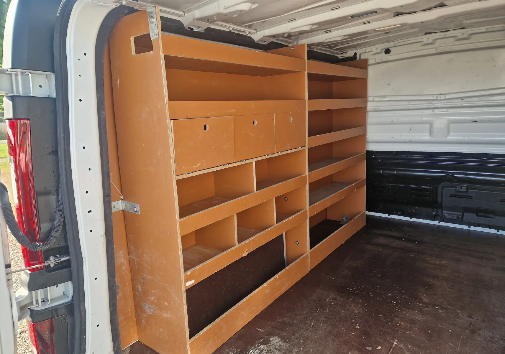 Vue intérieure arrière droite du Renault Trafic Fourgon blanc 2021 avec étagères en bois intégrées dans l’espace de chargement.