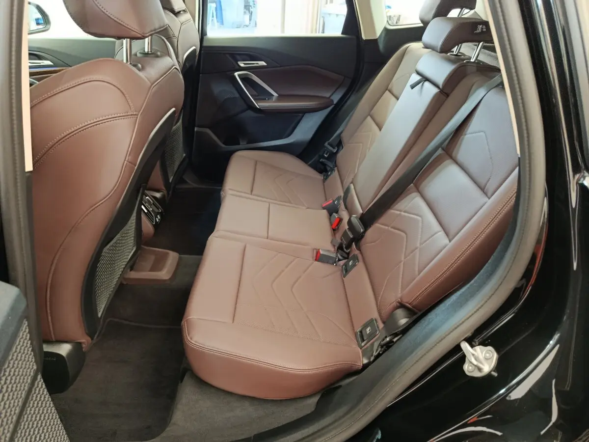 Vue intérieure arrière côté droit montrant la banquette marron en cuir du BMW X1 sDrive18i 2023 noir.
