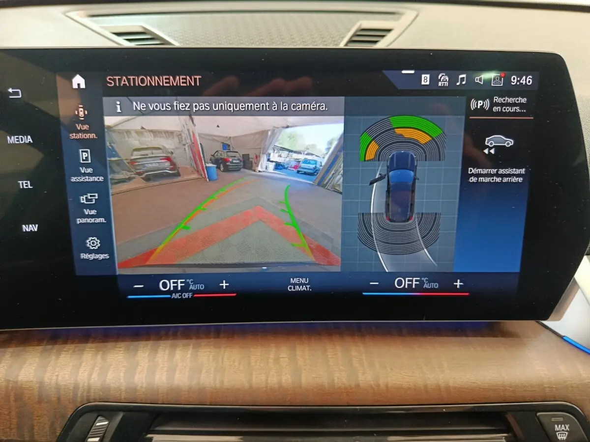 Écran tactile du tableau de bord du BMW X1 noir 2023 affichant l'aide au stationnement en marche arrière.